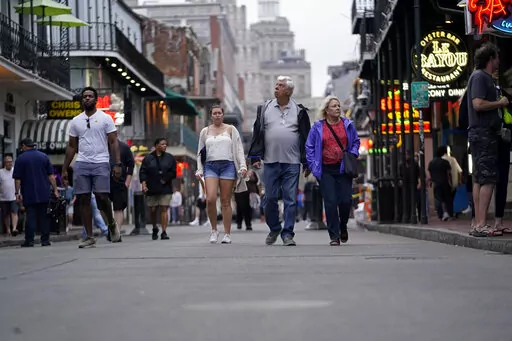 People walk in the French Quarter Wednesday, March 30, 2022., in New Orleans. Few things in the sports world resemble a return to pre-pandemic life more than an NCAA Final Four in sold-out Superdome -- and all that goes with it. Hotels and restaurants are heavily booked as a city famous for majors sports events, music festivals and cultural tourism gets the economic and reputational jolt it has needed after about two years of pandemic restrictions. (AP Photo/Gerald Herbert)