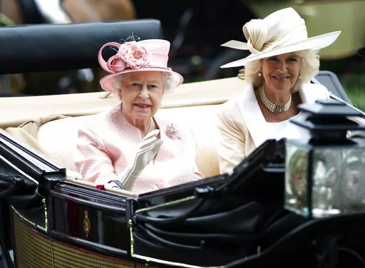 Britain's Queen Elizabeth II waves to the crowds with Camilla, Duchess of Cornwall  at right, as they arrive by carriage on the first day of the Royal Ascot horse race meeting in Ascot, England, Tuesday, June 18, 2013.  Queen Elizabeth II has offered her support to have the Duchess of Cornwall become Queen Camilla — using a special Platinum Jubilee message to make a significant decision in shaping the future of the monarchy. (AP Photo/Alastair Grant, File)