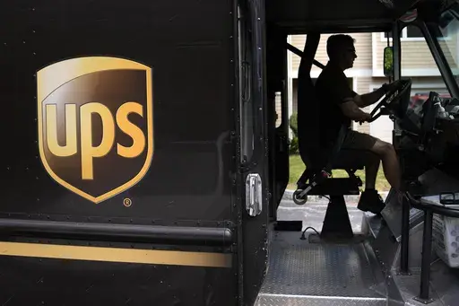 United Parcel Service driver Hudson de Almeida steers through a neighborhood while delivering packages, Friday, June 30, 2023, in Haverhill, Mass. UPS has reached a contract agreement with its 340,000-person strong union Tuesday, July 25, averting a strike that had the potential to disrupt logistics nationwide for businesses and households alike. (AP Photo/Charles Krupa, File)