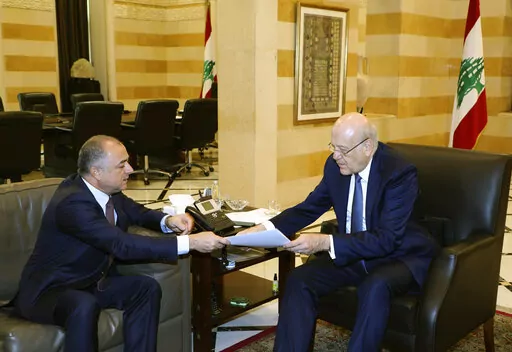 In this photo released by Lebanon's official government photographer Dalati Nohra, Lebanese Prime Minister Najib Makati, right, receives the final draft of the maritime border agreement between Lebanon and Israel from his deputy Elias Bou Saab who leads the Lebanese negotiating team, in Beirut, Lebanon, Tuesday, Oct. 11, 2022. Israel's prime minister said Tuesday that the country has reached an "historic agreement" with neighboring Lebanon over their shared maritime border after months of U.S.-b