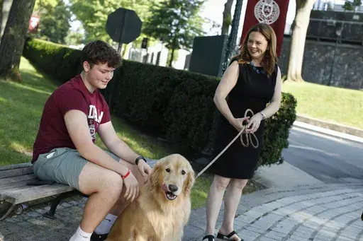 Tania Tetlow president of Fordham University holds her dog Archie as new students arrive during Move In Day at the Bronx campus, Sunday Aug. 25, 2024, in New York. (AP Photo/Kena Betancur)