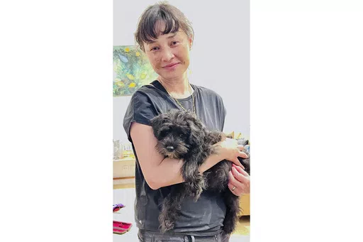 In this undated photo provided by the family of Jade Young and distributed by the New South Wales Police Jade Young holds a dog at an unknown location. Young, 47, was killed in a deadly attack at a Sydney shopping center on Saturday, April 13, 2024. (Courtesy of Young Family/NSW Police via AP)