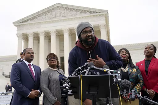 Evan Milligan, center, plaintiff in Merrill v. Milligan, an Alabama redistricting case, speaks with members of the press following oral arguments outside the Supreme Court on Capitol Hill in Washington, Oct. 4, 2022. Standing behind Milligan are Milligan's counsel Deuel Ross, from left, Letetia Jackson, Rep. Terri Sewell, D-Ala., and Janai Nelson, President and Director-Counsel of the NAACP Legal Defense Fund. The Supreme Court on Thursday, June 8, 2023, issued a surprising ruling in favor of Bl