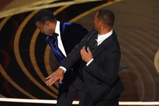 Will Smith, right, hits presenter Chris Rock on stage while presenting the award for best documentary feature at the Oscars on Sunday, March 27, 2022, at the Dolby Theatre in Los Angeles. Rock will be the first artist to perform on Netflix's first-ever live, global streaming event. (AP Photo/Chris Pizzello, File)