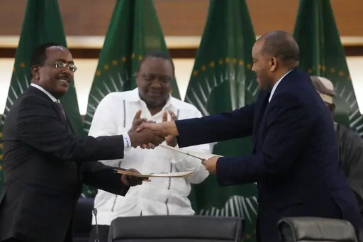 Lead negotiator for Ethiopia’s government, Redwan Hussein, left, shakes hands with lead Tigray negotiator Getachew Reda, as Kenya's former president, Uhuru Kenyatta looks on, after the peace talks in Pretoria, South Africa, Wednesday, Nov. 2, 2022. Ethiopia’s warring sides have formally agreed to a permanent cessation of hostilities, an African Union special envoy said Wednesday, after a 2-year conflict whose victims could be counted in the hundreds of thousands. (AP Photo/Themba Hadebe)