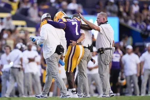 LSU head coach Brian Kelly, right, pats linebacker Harold Perkins Jr. (7) as he is helped off the field after being injured in the second half of an NCAA college football game against UCLA in Baton Rouge, La., Saturday, Sept. 21, 2024. LSU won 34-17. (AP Photo/Gerald Herbert)