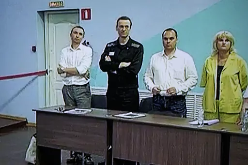 Russian opposition leader Alexei Navalny, 2nd left, is seen on a TV screen standing among his lawyers, as he appears in a video link provided by the Russian Federal Penitentiary Service, during a hearing in the colony, in Melekhovo, Vladimir region, about 260 kilometers (163 miles) northeast of Moscow, Russia, on Friday, Aug. 4, 2023. Navalny on Friday was convicted on extremism charges and sentenced to 19 years in prisons, in the harshest ruling against the imprisoned Kremlin critic to date. (A