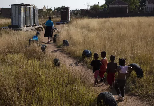 Children follow school manager, Florina Ledwaba, toward pit toilets at the Jupiter Pre-School and Creche, in the rural village of Ga-Mashashane, near Polokwane, South Africa, Thursday May 4, 2023. Human rights groups have been pressuring the government for a decade to get rid of pit toilets in schools, with the issue given added urgency by several tragic cases of young children falling into the pits and drowning. (AP Photo/Denis Farrell)