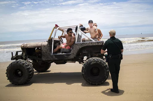 A group of people riding in a Jeep during the Go Topless Jeep Weekend event get stopped by a Galveston County Sheriff's Office deputy at Crystal Beach on Bolivar Peninsula, Texas, May 17, 2020. (Marie D. De Jesús/Houston Chronicle via AP, File)