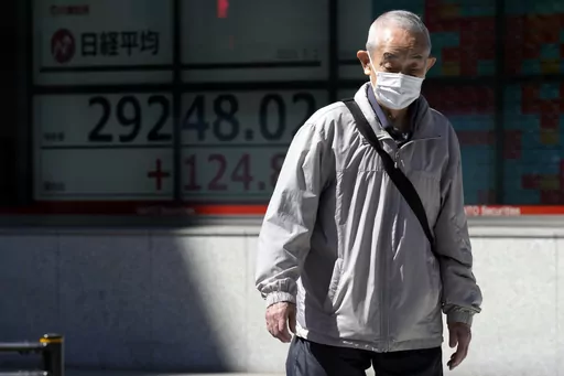 A person walks past an electronic stock board showing Japan's Nikkei 225 index at a securities firm Tuesday, May 2, 2023, in Tokyo. Asian shares were mixed Tuesday with some markets closed or anticipating holidays and investors showing muted reaction to the latest historic U.S. banking failure. (AP Photo/Eugene Hoshiko)
