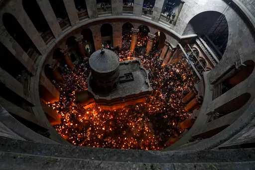 Christian pilgrims hold candles as they gather during the ceremony of the Holy Fire at Church of the Holy Sepulchre, where many Christians believe Jesus was crucified, buried and rose from the dead, in the Old City of Jerusalem dead, Saturday, April 23, 2022. (AP Photo/Tsafrir Abayov)