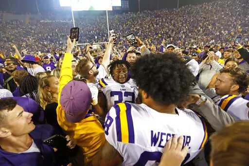 LSU offensive lineman Fitzgerald West Jr. (68) and linebacker DeMario Tolan (32) celebrate with fans who stormed the field after an NCAA college football game against Alabama in Baton Rouge, La., Saturday, Nov. 5, 2022. (AP Photo/Tyler Kaufman)