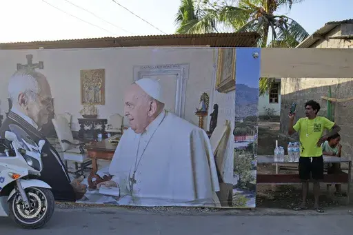A man stands near a banner showing East Timor's President Jose Ramos-Horta, left, shaking hands with Pope Francis, ahead of the pope's visit to the country, in Dili, Saturday, Sept. 7, 2024. (AP Photo/Dita Alangkara)