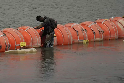 A migrant from Columbia stands at a floating buoy barrier as he looks to cross the Rio Grande from Mexico into the U.S., Monday, Aug. 21, 2023, in Eagle Pass, Texas. (AP Photo/Eric Gay)