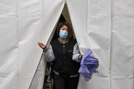 A woman wearing a face mask to help protect from the coronavirus walks out from a tent after getting a COVID-19 test, Tuesday, March 29, 2022, in Beijing. A two-phase lockdown of Shanghai's 26 million people is testing the limits of China's hard-line "zero-COVID" strategy, which is shaking markets far beyond the country's borders. (AP Photo/Andy Wong)