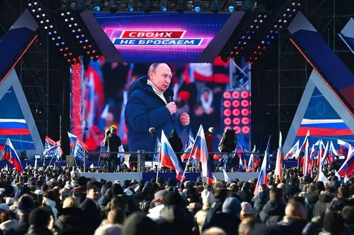 Russian President Vladimir Putin seen on the big screen as he delivers his speech at the concert marking the eighth anniversary of the referendum on the state status of Crimea and Sevastopol and its reunification with Russia, in Moscow, Russia, Friday, March 18, 2022, with a banner reading "For Russia" projected in the backgroud. (Vladimir Astapkovich/Sputnik Pool Photo via AP)