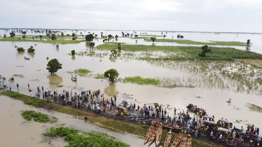 People walk through floodwaters with flooded farmlands forground after heavy rainfall in Hadeja, Nigeria, Sept 19, 2022. West and Central African countries are battling deadly floods that have upended lives and livelihoods, raising fears of further disruption of food supplies in many areas battling armed conflict. “Above-average rainfall and devastating flooding” have affected 5 million people this year in 19 countries across West and Central Africa, according to a new U.N. World Food Progra