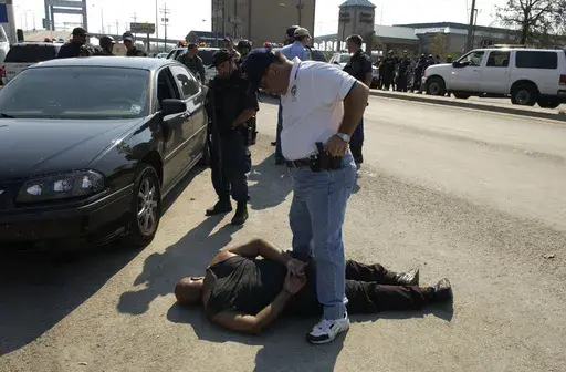 Morrell Johnson of New Orleans, is detained by NOPD Sgt. Arthur Kaufman on the Gentilly side of the Danziger Bridge, September 4, 2005. (Alex Brandon/The Times-Picayune/The New Orleans Advocate via AP)