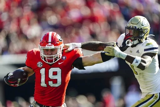 Georgia tight end Brock Bowers (19) fends off Georgia Tech defensive back Zamari Walton (7) as he run after a catch during the first half of an NCAA college football game Saturday, Nov. 26, 2022 in Athens, Ga. Bowers was called for a face masking penalty. (AP Photo/John Bazemore)