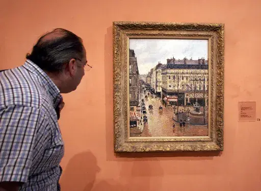 A visitor views the Impressionist painting called "Rue St.-Honore, Apres-Midi, Effet de Pluie" (“Rue Saint-Honoré in the Afternoon, Effect of Rain") painted in 1897 by Camille Pissarro, on display in the Thyssen-Bornemisza Museum May 12, 2005, in Madrid. (AP Photo/Mariana Eliano, File)