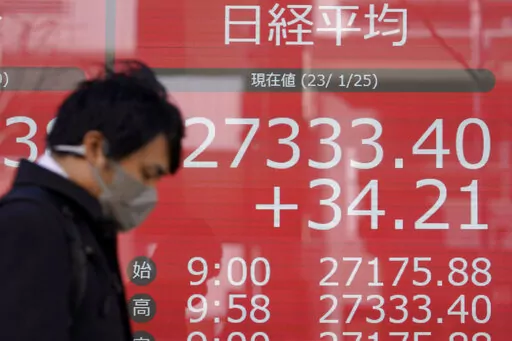 A person wearing a protective mask walks in front of an electronic stock board showing Japan's Nikkei 225 index at a securities firm Wednesday, Jan. 25, 2023, in Tokyo. Asian shares were mixed Wednesday after Wall Street indexes finished little changed as investors awaited earnings results from major global companies. (AP Photo/Eugene Hoshiko)