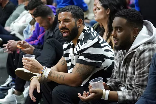 The rapper Drake, front left, looks on during the second half of an NBA basketball game between the Miami Heat and the Atlanta Hawks, Friday, Jan. 14, 2022, in Miami. (AP Photo/Lynne Sladky)