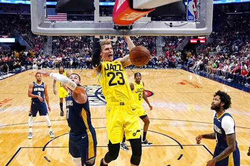 Utah Jazz forward Lauri Markkanen (23) slam dunks over New Orleans Pelicans center Jonas Valanciunas, left, and forward Brandon Ingram, right, in the first half of an NBA basketball game in New Orleans, Sunday, Oct. 23, 2022. (AP Photo/Gerald Herbert)