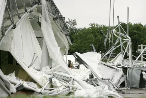 A fire fighter, center, stands surrounded by the collapsed canopy that covered the Dallas Cowboys indoor practice facility in Irving, Texas, on May 2, 2009. (AP Photo/Tony Gutierrez, File)