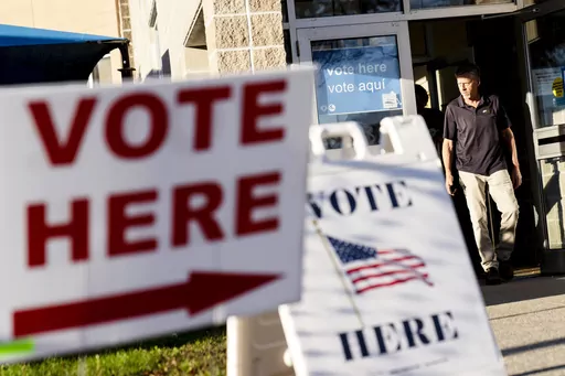 Signs point to the entrance on the last day of early voting before the midterm election as a man walks out of a polling site in Cranston, R.I., on Nov. 7, 2022. Almost half of all voters in the 2022 midterm elections cast their ballots before Election Day either by mail or through early voting, with Asian and Hispanic voters leading the way, new data from the U.S. Census Bureau released Tuesday, May 2, 2023, shows, even as Republican-led states have tightened rules on voting by mail. (AP Photo/D