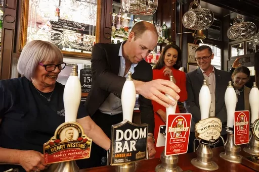 Britain's Prince William pulls the first pint of Kingmaker, a new brew celebrating the coronation of King Charles III, as he and the Princess of Wales visit the Dog & Duck pub in London, Thursday, May 4, 2023, to hear how it's preparing for the coronation of King Charles III and the Queen Consort at the weekend. (Jamie Lorriman/Pool Photo via AP)