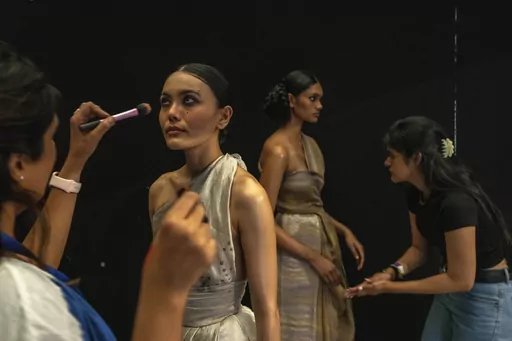 Makeup artists give final touches to models backstage before the start of a show during the Lakme Fashion Week X FDCI in Mumbai, India, Thursday, March. 9, 2023. From the front-row seats, fashion shows could be mistaken for a spectacular party with models sashaying down the ramp in stunning ensembles. But this confluence of fashion, designers, celebrities and buyers is hardly possible without an army of people furiously working behind the scenes to make sure the show goes smoothly. (AP Photo/Raf