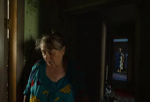 70-year-old Valentyna Klymenko, who lives alone in her war-damaged building from Russian aerial bombs, walks in her hallway, in Borodyanka, Kyiv region, Ukraine, Tuesday, June 28, 2022. Then Klymenko returns, alone, to an apartment that used to be noisy and full of life. Now, instead of the voices of her great-grandchildren, she is greeted by dim, damp rooms. She rarely cooks. She drinks fruit compote and eats canned tomatoes, which she prepared last year, so as not to waste the gas in her porta