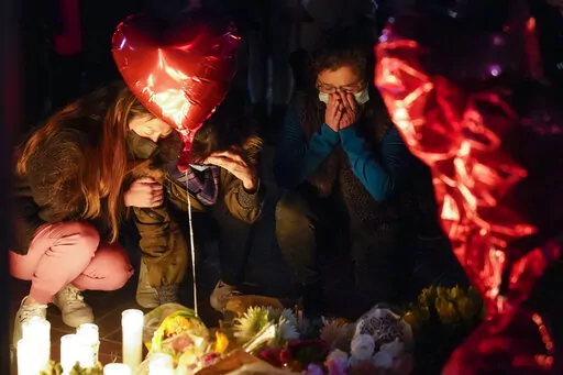 Women pause at a memorial at a vigil honoring the victims of a shooting at the Star Ballroom Dance Studio on Monday, Jan. 23, 2023, in Monterey Park, Calif. A gunman killed multiple people late Saturday amid Lunar New Years celebrations in the predominantly Asian American community. (AP Photo/Ashley Landis)