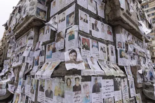 Portraits of missing people whose families say they were taken by the Assad regime are plastered across a monument in Damascus, Syria, Saturday, Dec. 28, 2024 (AP Photo/Mosa'ab Elshamy)