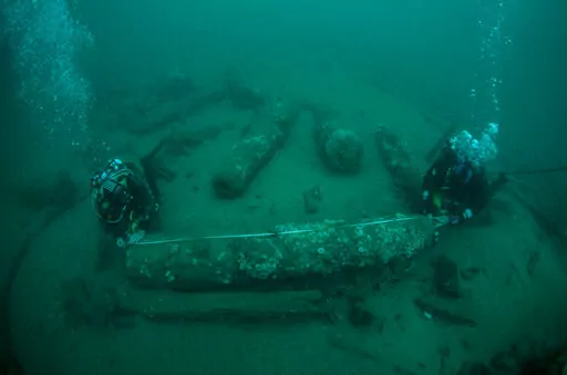 In this undated photo provided by Norfolk Historic Shipwrecks, Julian And Lincoln Barnwell measure the cannon found on the HMS Gloucester in 2007. Excavators and historians are telling the world about the wreck of a royal warship that sank in 1682 while carrying the future king James Stuart. The HMS Gloucester ran aground while navigating sandbanks off the town of Great Yarmouth on the eastern English coast. The wreck of the Gloucester was found in 2007 by brothers Julian and Lincoln Barnwell an