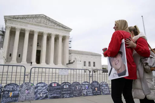 Jen Trejo holds a photo of her son Christopher as she is comforted outside the Supreme Court Monday, Dec. 4, 2023, in Washington. Her son was 32 when he died and she said about Purdue Pharma and the Sackler family, "You can't just kill my child and just pay a fine." The Supreme Court is wrestling with a nationwide settlement with OxyContin maker Purdue Pharma that would shield members of the Sackler family who own the company from civil lawsuits over the toll of opioids. (AP Photo/Stephanie Scar