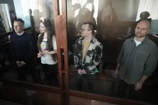 Russian journalists, from left, Konstantin Gabov, Antonina Favorskaya, Artyom Kriger and Sergey Karelin, accused of working for a group founded by the late Russian opposition politician Alexei Navalny, stand in a defendant's cage of the Nagatinsky District Court in Moscow, Russia, on Wednesday, Oct. 2, 2024. (AP Photo)