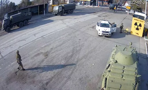 A frame grab taken by the battery-operated camera placed by Chernobyl Tour to show the company’s tourist information center near the Chernobyl nuclear power plant, shows Russian military vehicles rolling into Chernobyl, the site of the world's worst nuclear disaster, on the second day of the war, in the village of Dytyatki, Ukraine, on Friday, Feb. 25, 2022. (Yaroslav Yemelianenko/Chernobyl Tour via AP)