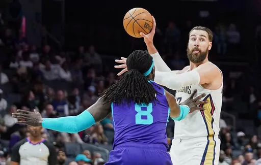 New Orleans Pelicans center Jonas Valanciunas, right, looks to pass around Charlotte Hornets center Montrezl Harrell (8) during the first half of an NBA basketball game on Monday, March 21, 2022, in Charlotte, N.C. (AP Photo/Rusty Jones)