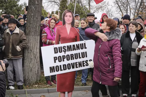 A woman slaps a cardboard cutout of Moldova's pro-western President Maia Sandu, with writing reading "Enemy of the Moldovan People", during a protest initiated by the populist Shor Party, in Chisinau, Moldova, Sunday, Nov. 13, 2022. Shor, a fugitive Moldovan oligarch and opposition leader has been sentenced in absentia to 15 years in jail for his alleged role in a one-billion-dollar bank fraud case, Moldova's President said. The Court of Appeal in the capital, Chisinau, sentenced Ilan Shor, who 