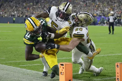 Green Bay Packers wide receiver Jayden Reed (11) is pushed out of bounds near the goal line by New Orleans Saints cornerback Will Harris (5) and linebacker Pete Werner (20) during the first half of an NFL football game, Monday, Dec. 23, 2024, in Green Bay, Wis. (AP Photo/Matt Ludtke)