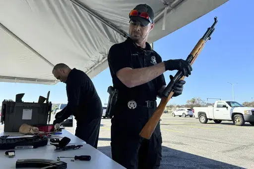 New Orleans police officer John Mciver dismantles a firearm handed over as part of a city-supported initiative exchanging guns for PlayStations, Tuesday, Dec. 31, 2024, in New Orleans. (AP Photo/Jack Brook)