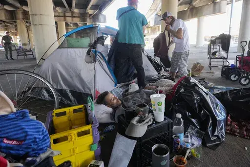 People living in a homeless encampment pick up belongings after Louisiana State police gave instructions for them to move to a different pre-designated location as they perform a sweep in advance of a Taylor Swift concert in New Orleans, Oct. 23, 2024. (AP Photo/Gerald Herbert, File)
