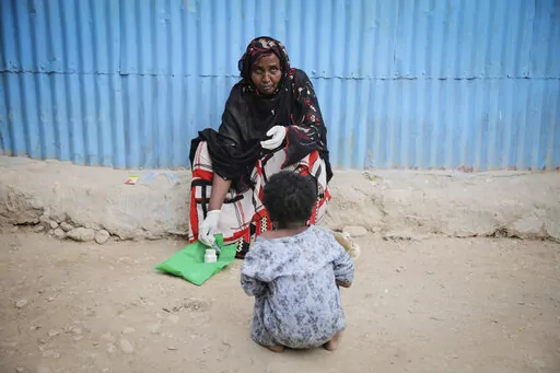 Safia Ibrahim demonstrates for the camera the tools and techniques she uses to perform female genital mutilation (FGM), which she learned at the age of 15 and has been practising for 35 years, as her neighbours daughter looks on in the courtyard of her home in Hargeisa, Somaliland, a semi-autonomous breakaway region of Somalia, on Feb. 7, 2022. Officials and health workers say cases of female genital mutilation increased during the pandemic in parts of Africa and particularly in Somaliland where