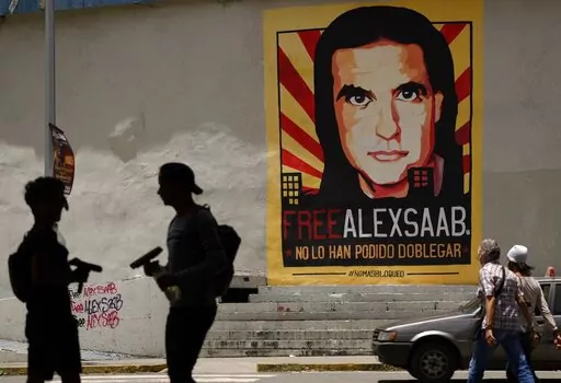 In this Sept. 9, 2021 file photo, pedestrians walk near a poster of Alex Saab that reads in Spanish "Alex Saab Free. They haven't been able to bend him," in Caracas, Venezuela. Newly unsealed court records show that the Colombian businessman linked to Venezuelan President Nicolas Maduro was secretly signed up by the D.E.A. as a cooperating source in 2018 and gave agents information about bribes he paid to Venezuelan officials. However, he was deactivated as a source after failing to meet a deadl
