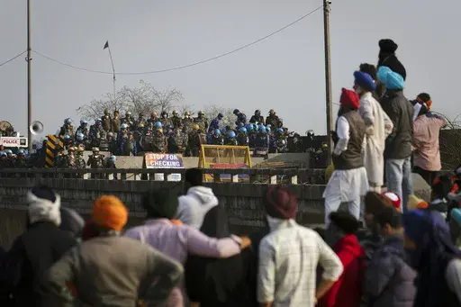 Protesting farmers stand facing the police barricade near Shambhu border that divides northern Punjab and Haryana states, almost 200 kilometers (125 miles) from New Delhi, India, Friday, Feb.16, 2024. Farmers are blocking highways and holding demonstrations in many rural areas in northern India to protest over a range of grievances that have also led tens and thousands to march toward the capital. (AP Photo/Altaf Qadri)