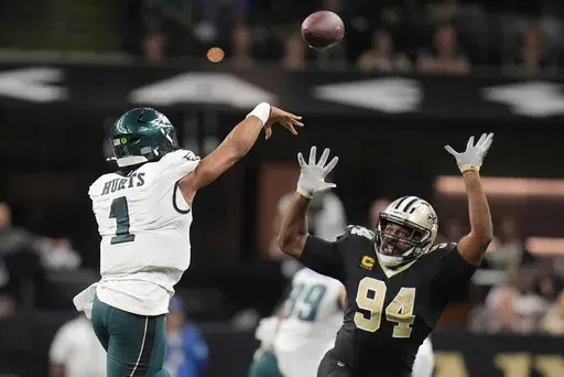 Philadelphia Eagles quarterback Jalen Hurts (1) passes over the reach of New Orleans Saints defensive end Cameron Jordan (94) in the second half of an NFL football game in New Orleans, Sunday, Sept. 22, 2024. (AP Photo/Gerald Herbert)