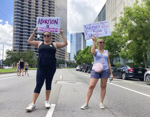 Protesters wave signs and demonstrate in support of abortion access in front of a New Orleans courthouse Friday July 8, 2022. Inside the courthouse a judge was hearing arguments on the state's trigger law designed to outlaw almost all abortions. (AP Photo/Rebecca Santana)