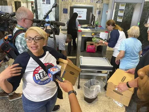 Eileen Carter, an organizer of a recall petition drive against New Orleans Mayor LaToya Cantrell, holds a box of petitions as others are put through security equipment at New Orleans City Hall on Wednesday, Feb. 22, 2023. Organizers say they have enough signatures to force a recall referendum on Cantrell. (AP Photo/Kevin McGill)