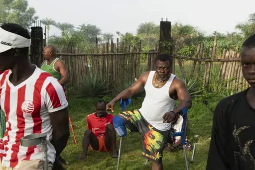 Farming trainees who have been amputated during Sierra Leone's civil war from 1991-2002, do warmup exercises before starting their day at the Farming on Crutches initiative in Freetown, Sierra Leone, Wednesday, Sept. 25, 2024. (AP Photo/Jack Thompson)